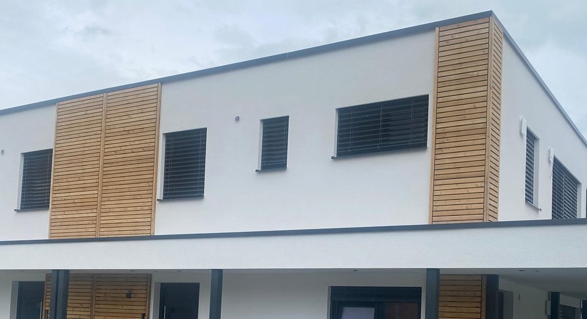 Wohnhaus mit weißer Putzfassade und Holzverkleidung als Beispiel für massive Bauweise
